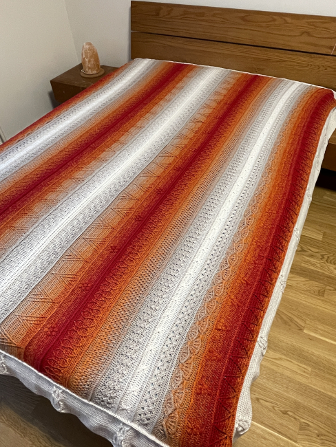 Fertige Zauberdecke aus Farbverlaufsgarn, ausgebreitet auf einem Sofa